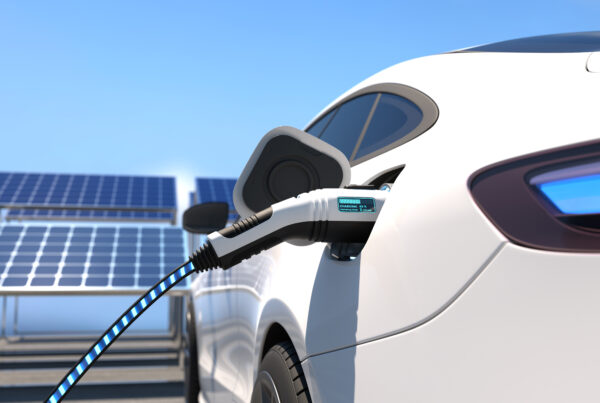 Electric vehicle charging with solar power, featuring solar panels in the background.