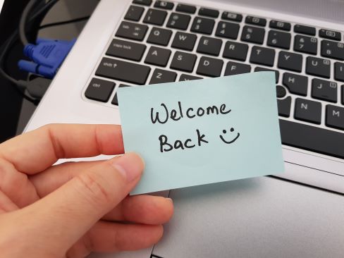Welcome back note held in front of laptop keyboard